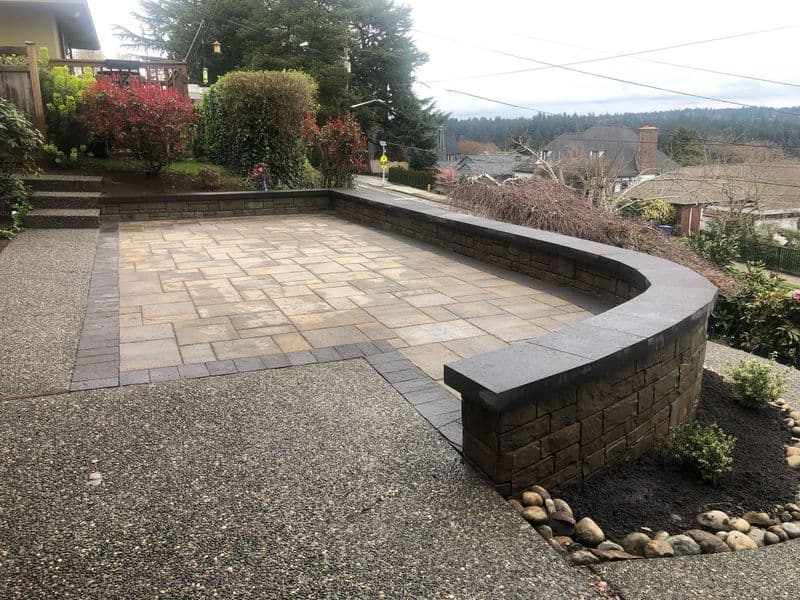 Elegant stone patio with curved seating area and lush greenery in a residential garden.