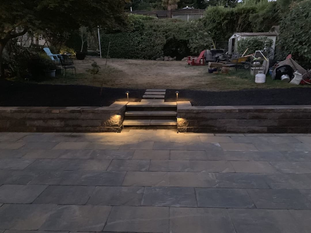 Backyard entrance with illuminated stone steps and landscaped garden, creating a welcoming ambiance.
