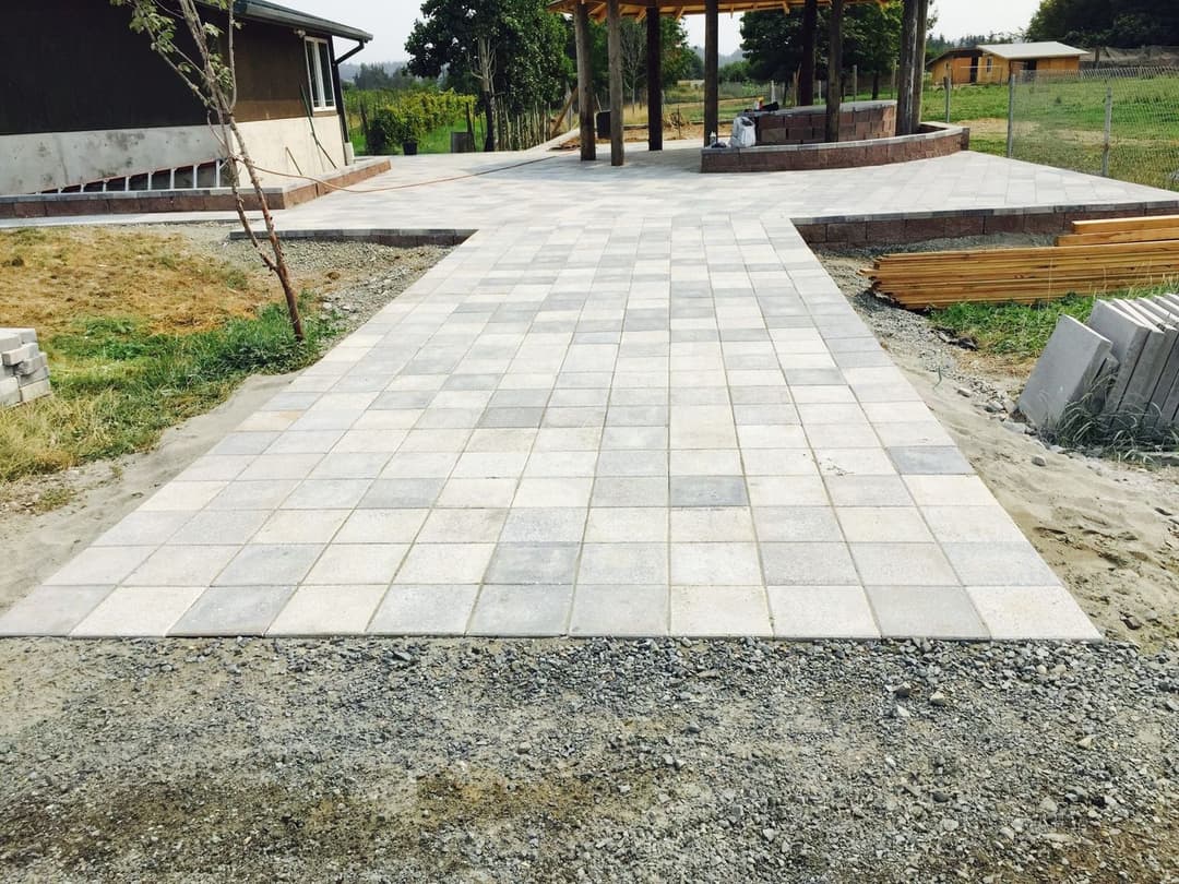 Paved outdoor patio area with stone tiles, surrounded by grass and landscaping.