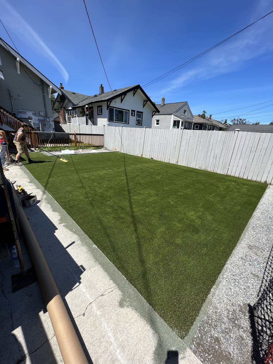 Artificial turf installation in a residential backyard with clear blue skies.