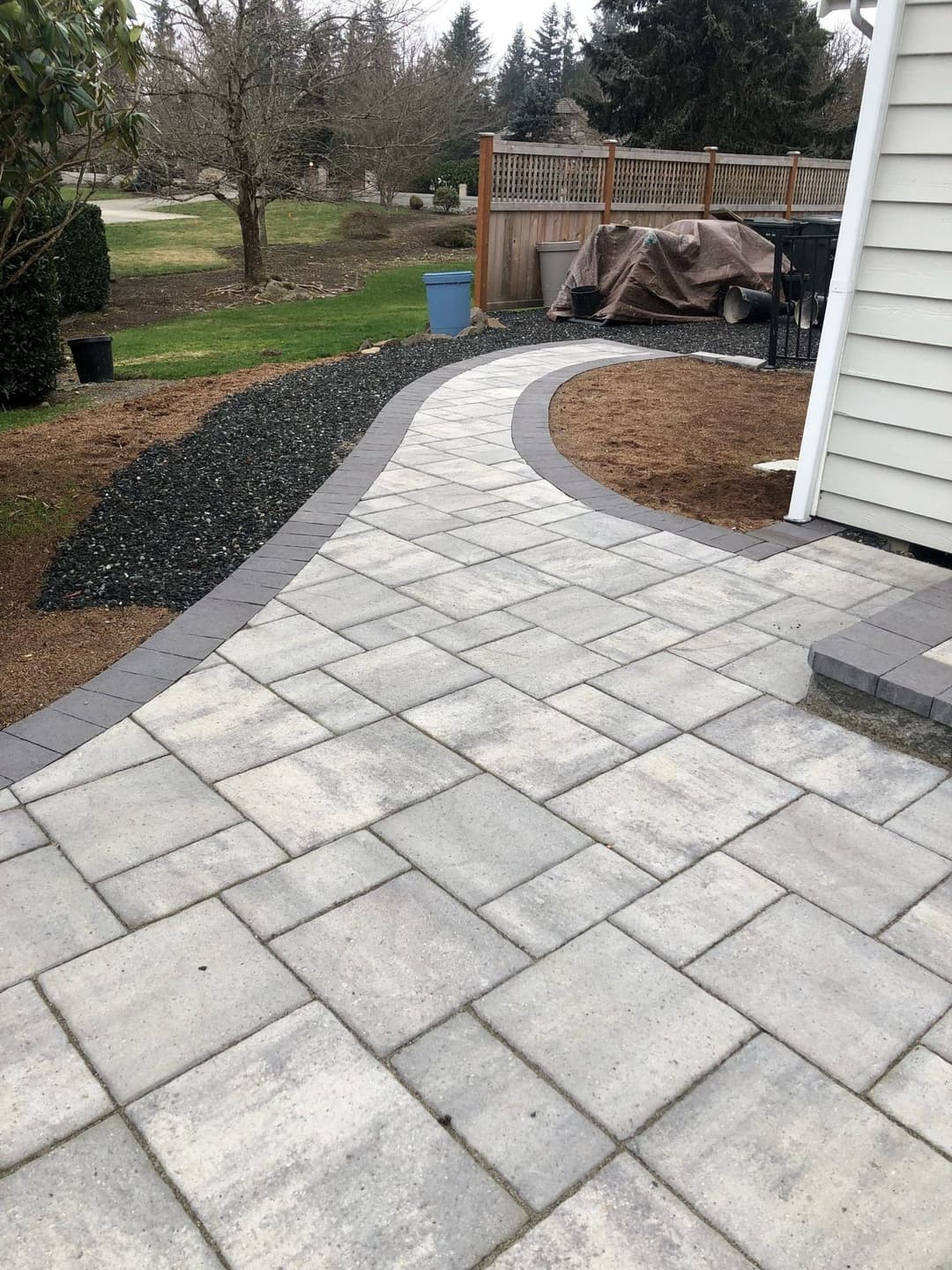 Curved stone pathway in a residential yard with gravel and landscaping features.