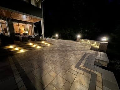 Illuminated outdoor patio at night showcasing elegant paver design and cozy seating area.